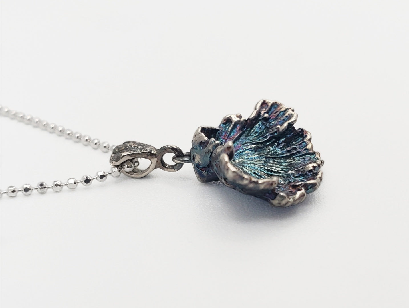 Oxidized sterling silver fungi pendant with ruffled edge. Shown at a sideways angle.