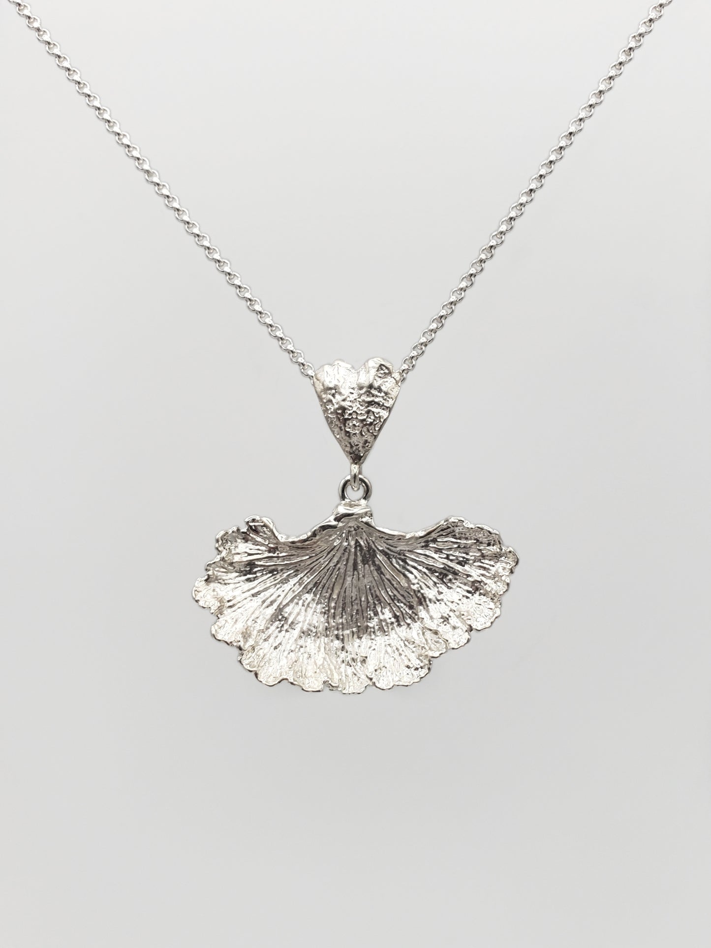 Sterling silver fungi pendant with a ruffled edge and gills showing.