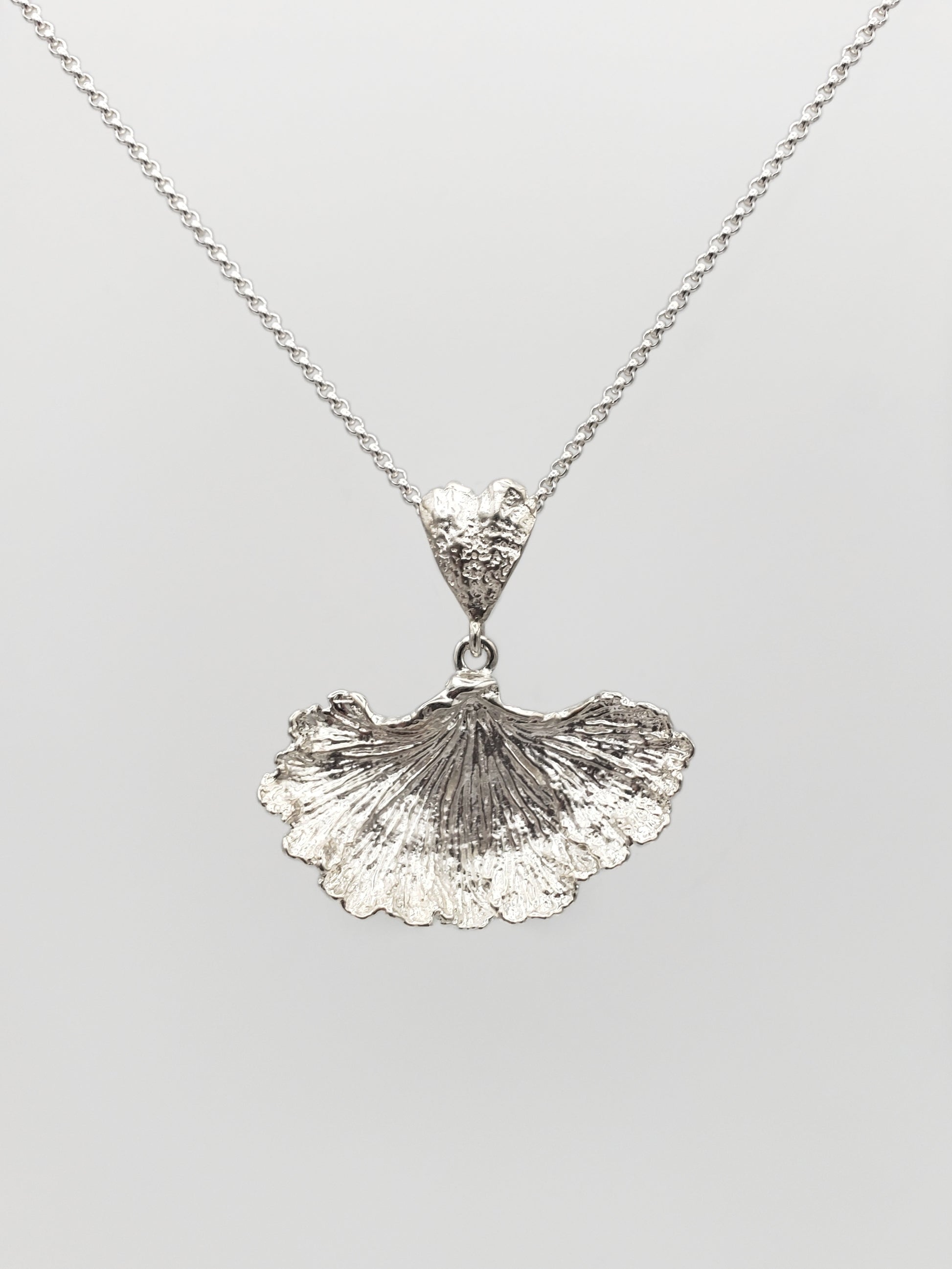Sterling silver fungi pendant with a ruffled edge and gills showing.