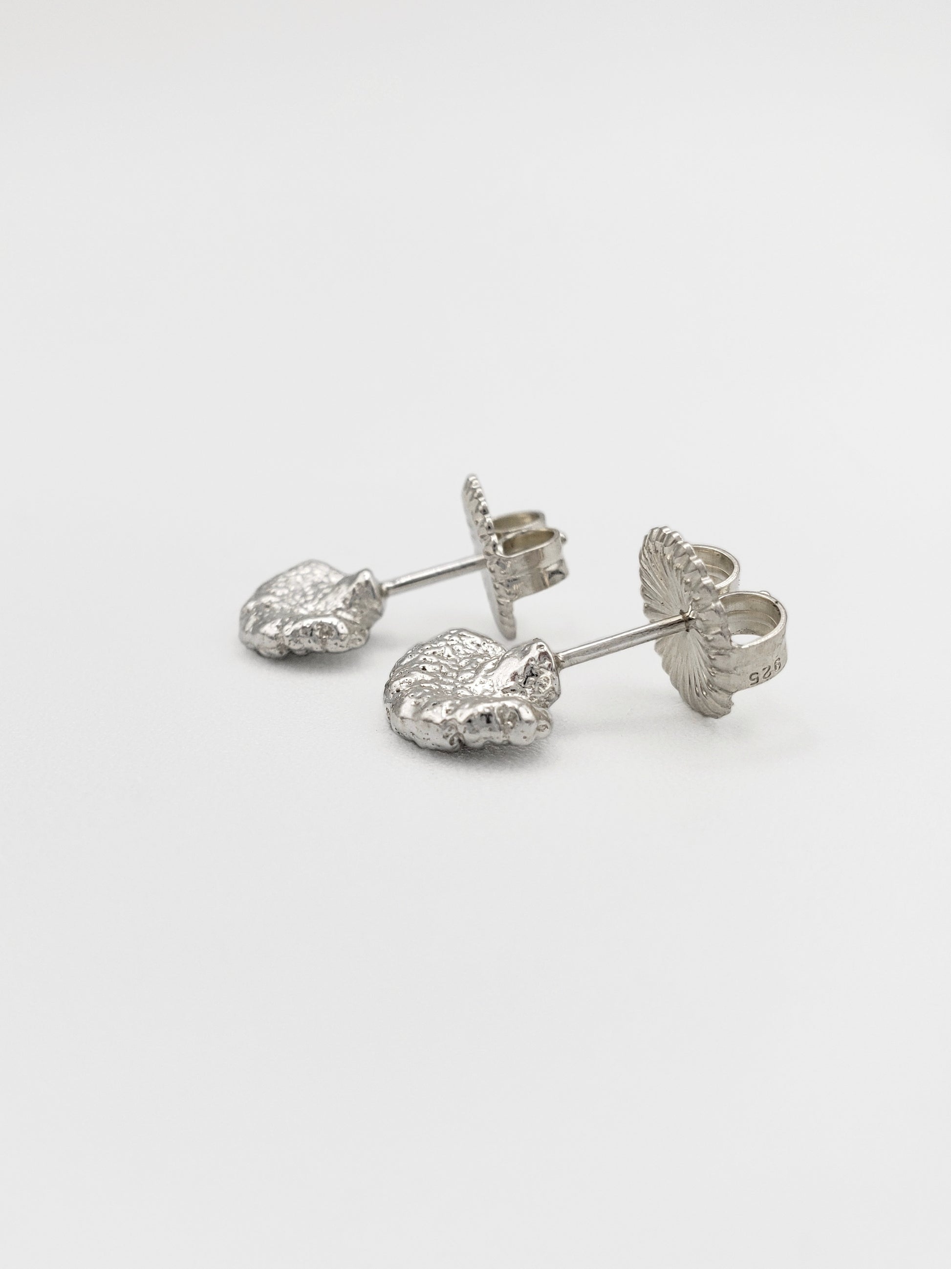 Sterling silver fungus stud earrings with large butterfly backs. Shown from a side view.
