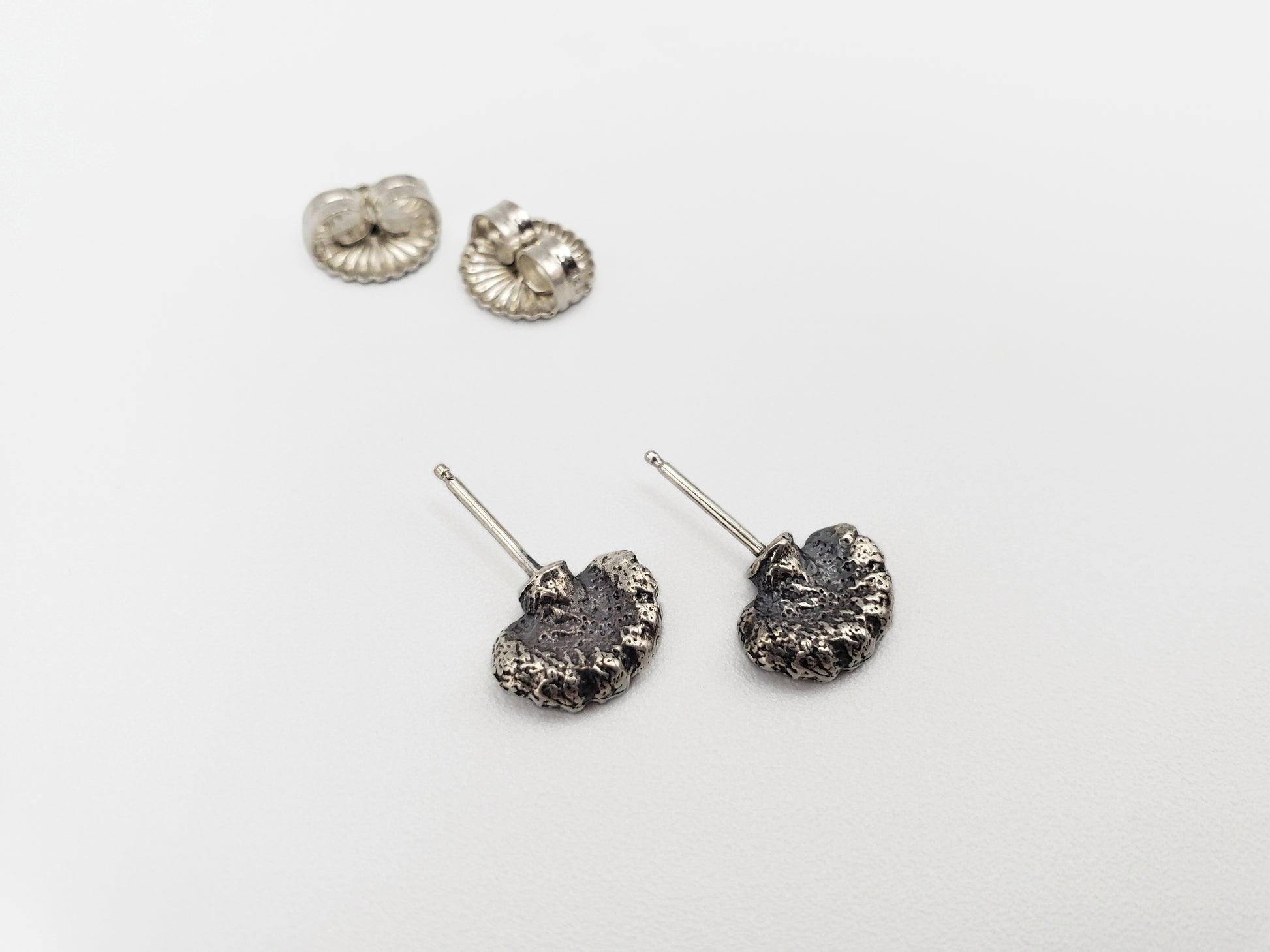 Oxidized sterling silver fungus stud earrings with large butterfly backs in the background