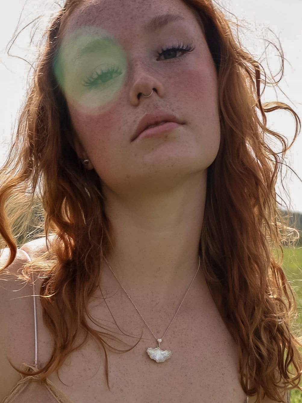 Red haired woman in the sun wearing a sterling silver fungi pendant.