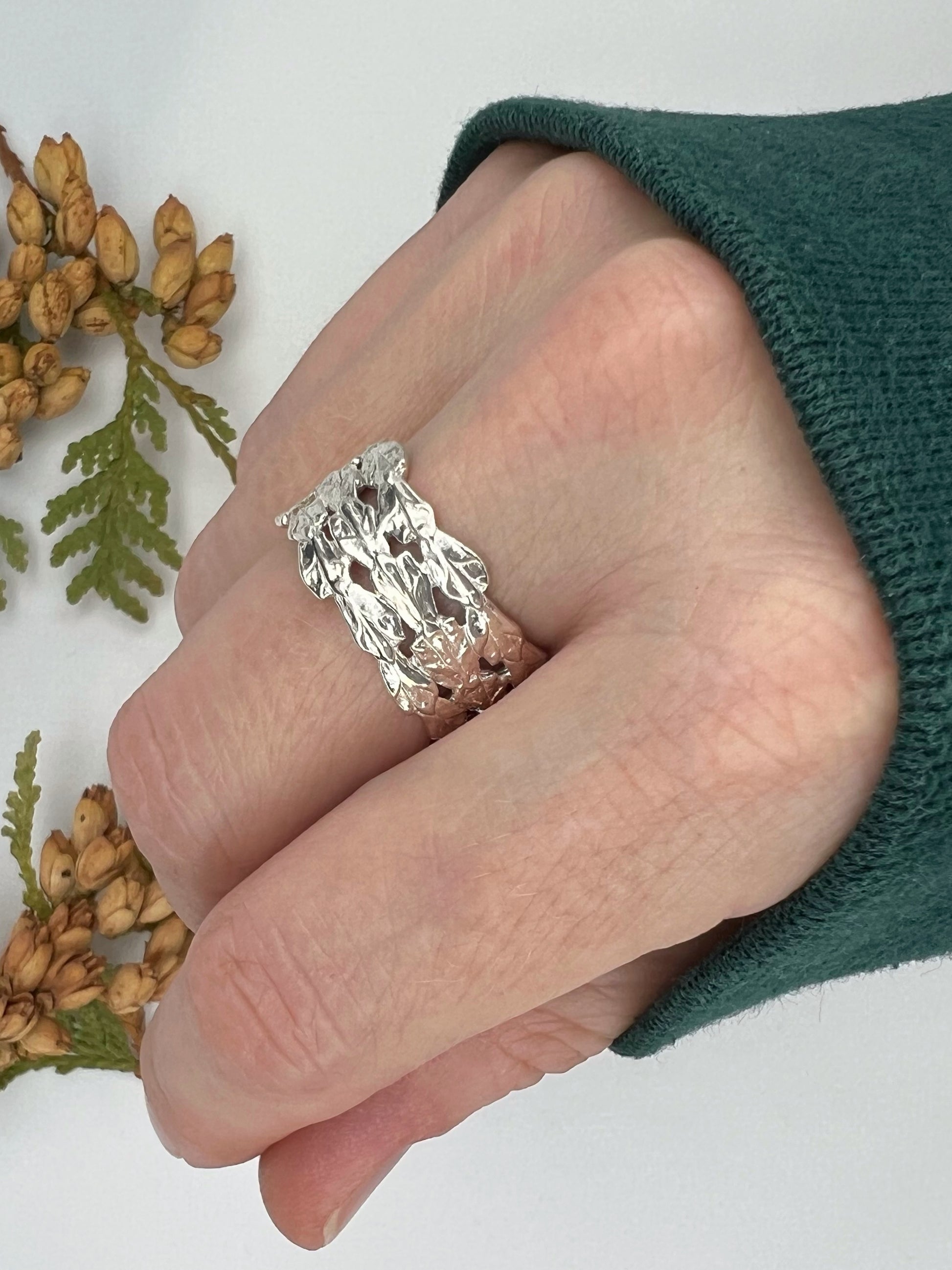 Woman's hand wearing a sterling silver triple cedar ring with three bold bands, cast from real cedar.