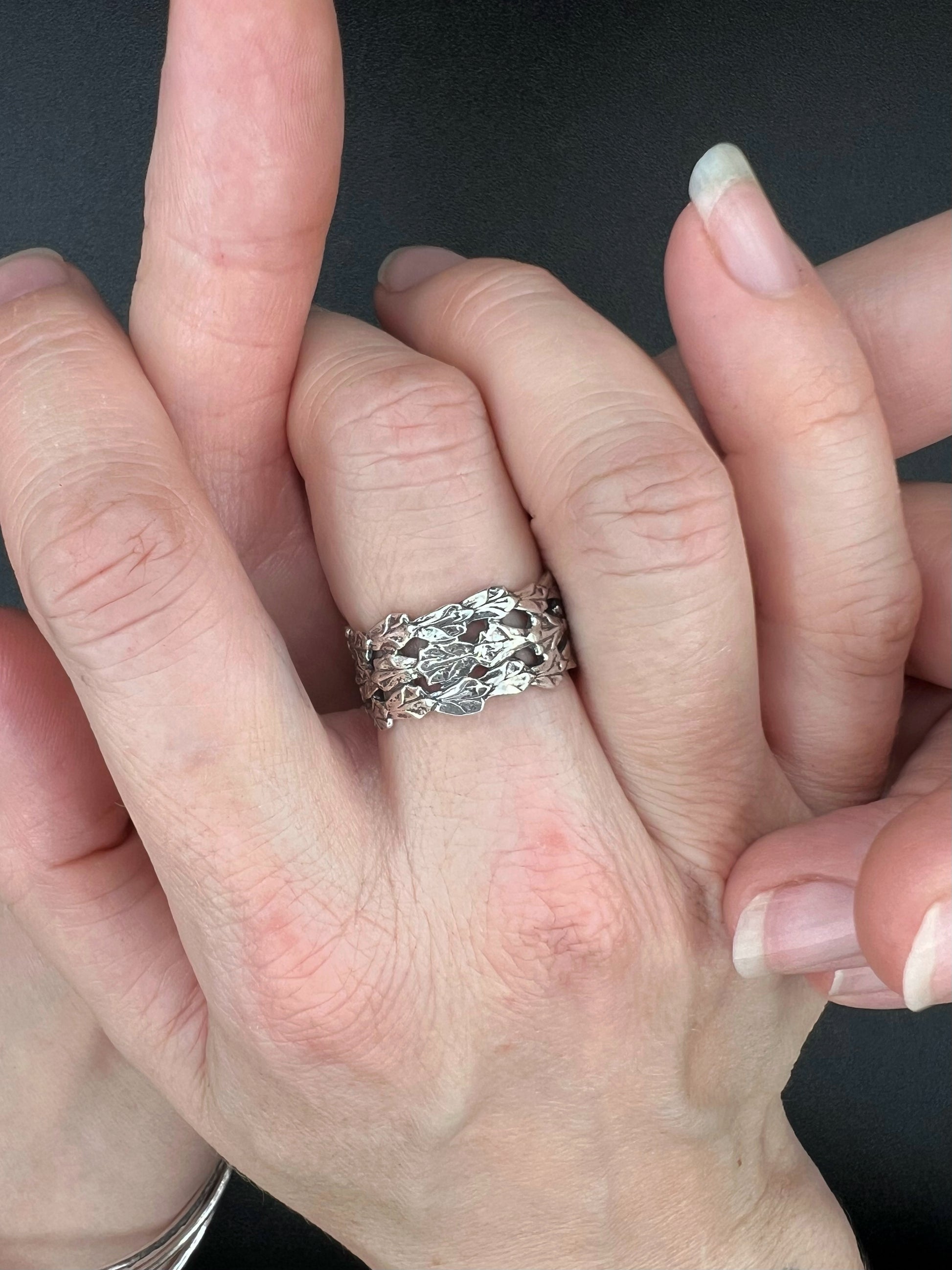 Women's clasped hands wearing an oxidized sterling silver triple cedar ring with three bold bands, cast from real cedar.
