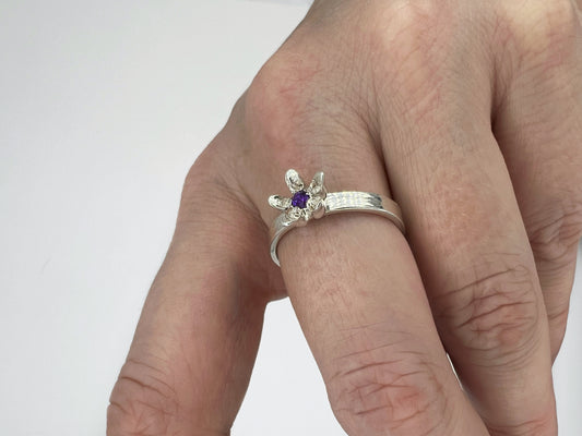 silver ring with milkweed flower and amethyst center, worn on a hand