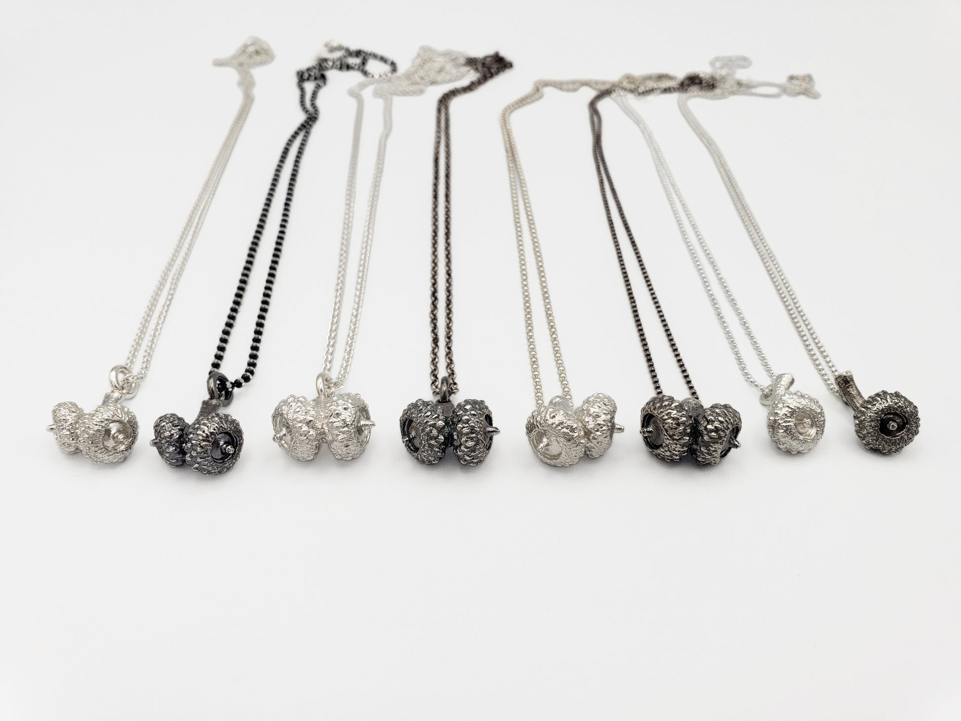 Eight silver acorn pendants. Alternating between silver colour and oxidized grey colour