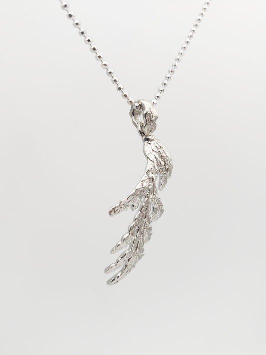 Sterling silver cedar pendant shown at an extreme sideways angle.