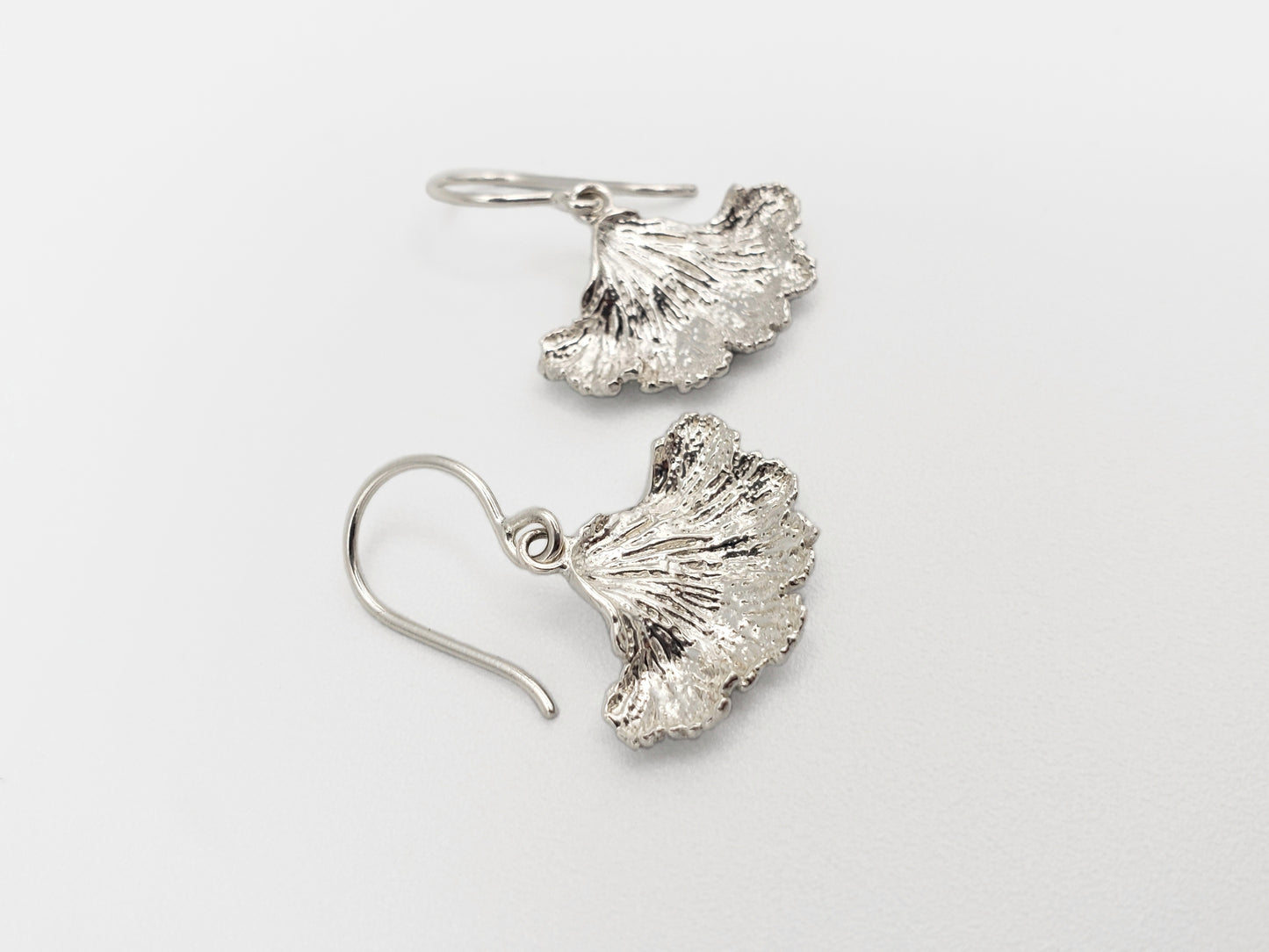 Sterling silver fungi earrings with a ruffled edge shown from a sideways angle.