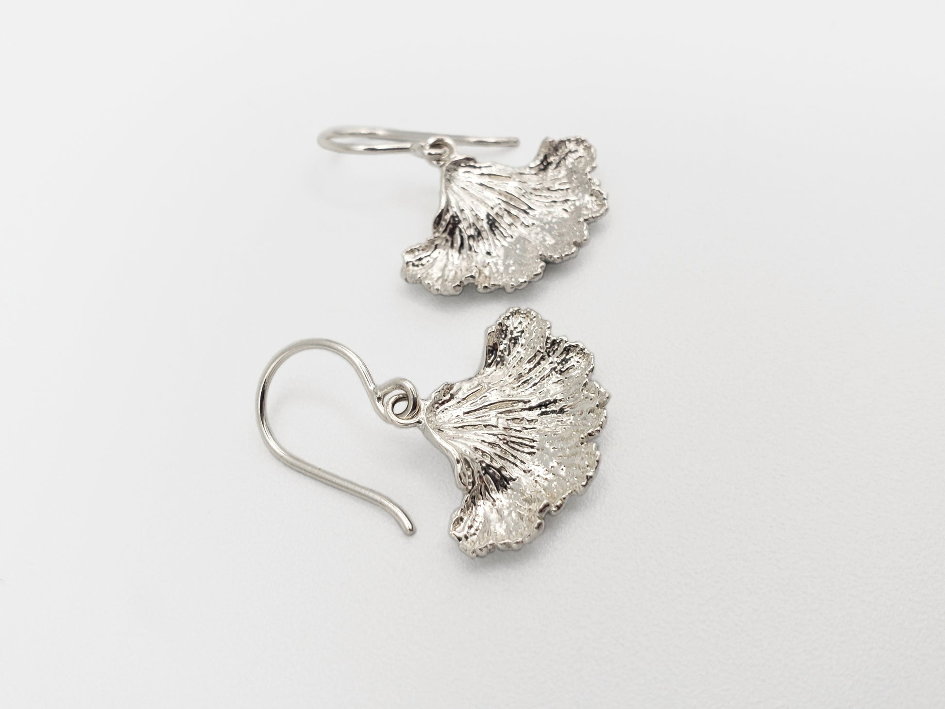 Sterling silver fungi earrings with a ruffled edge shown from a sideways angle.