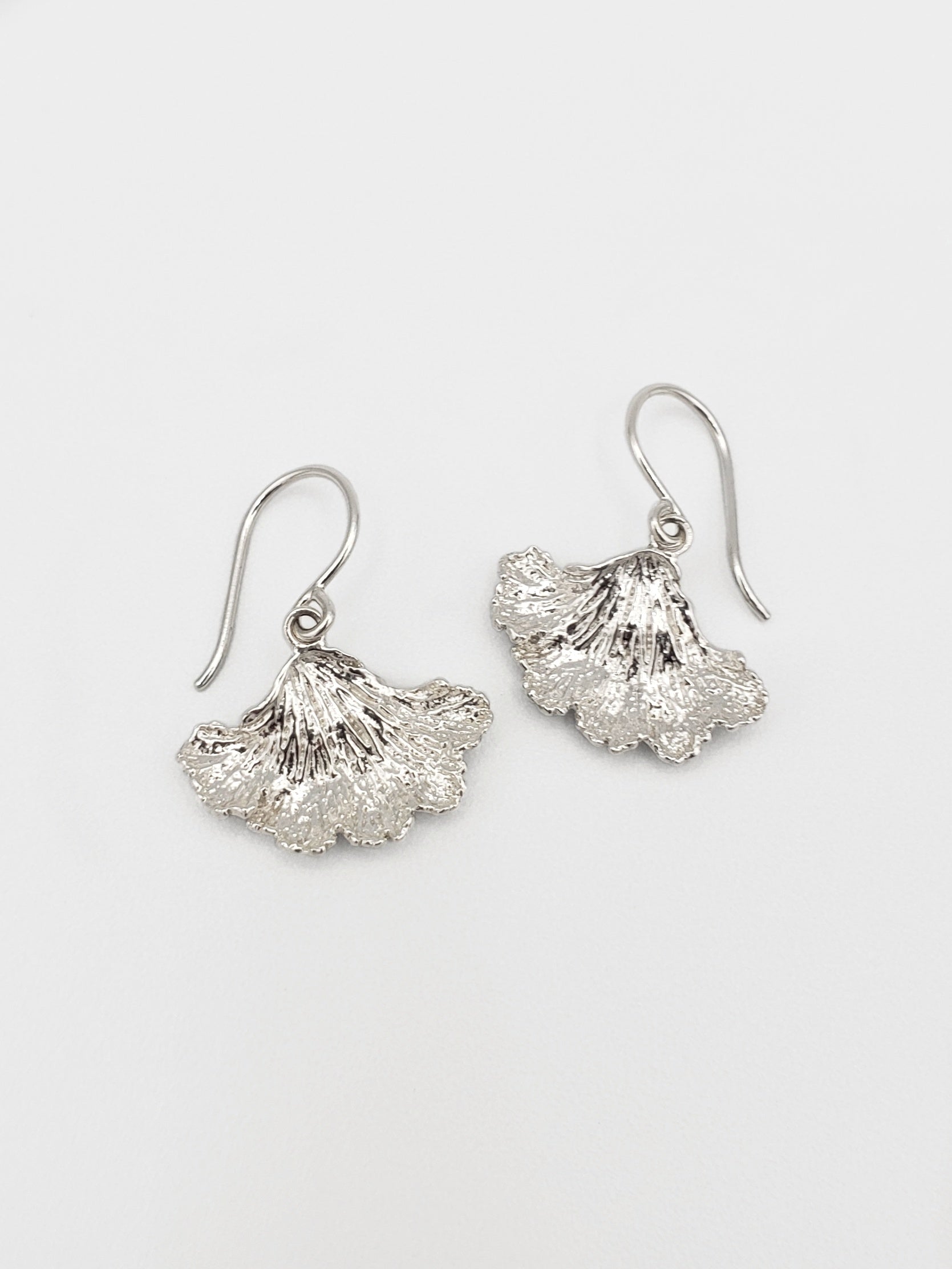 Sterling silver fungi earrings with a ruffled edge.