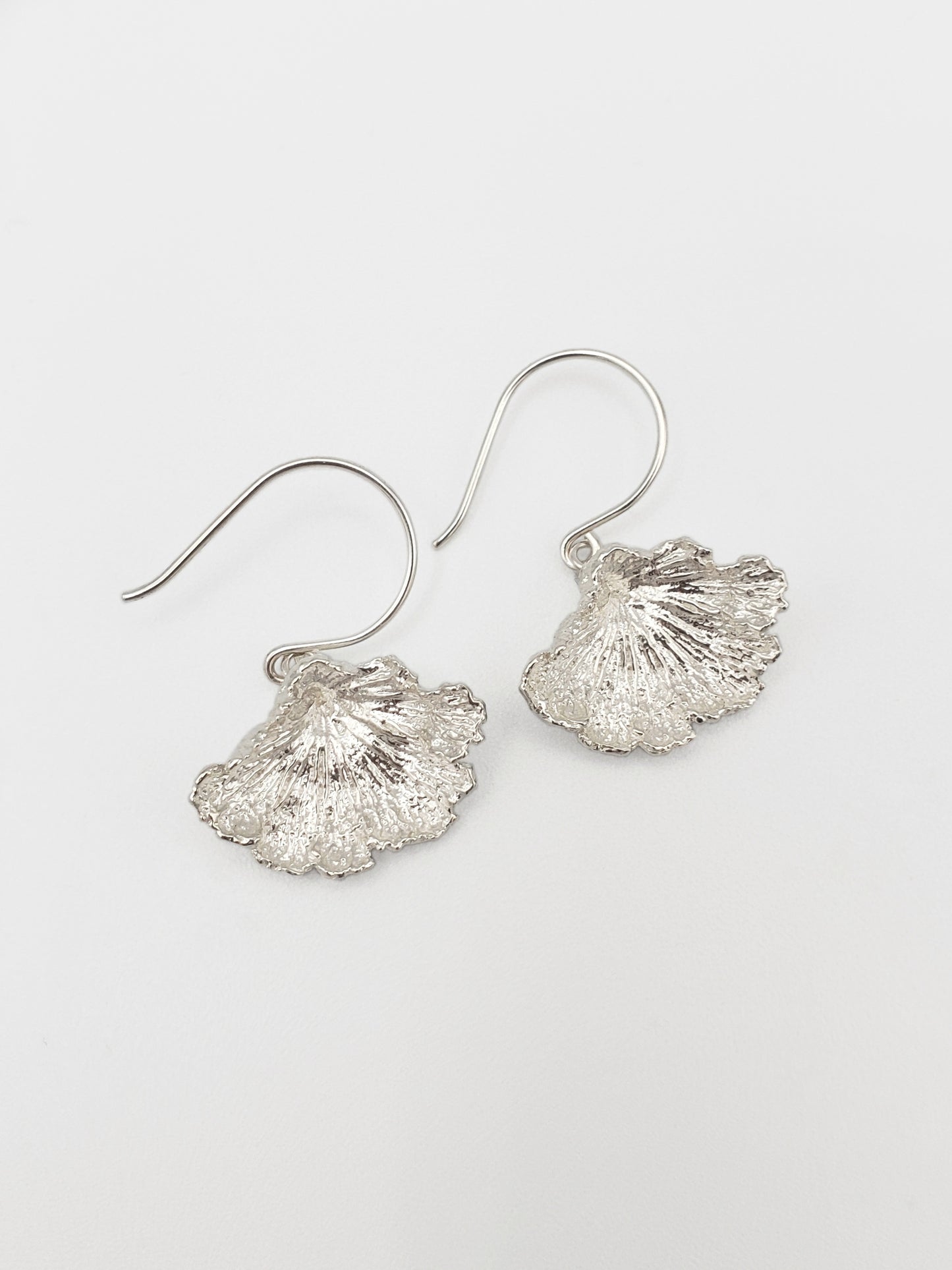 Sterling silver fungi earrings with a ruffled edge.