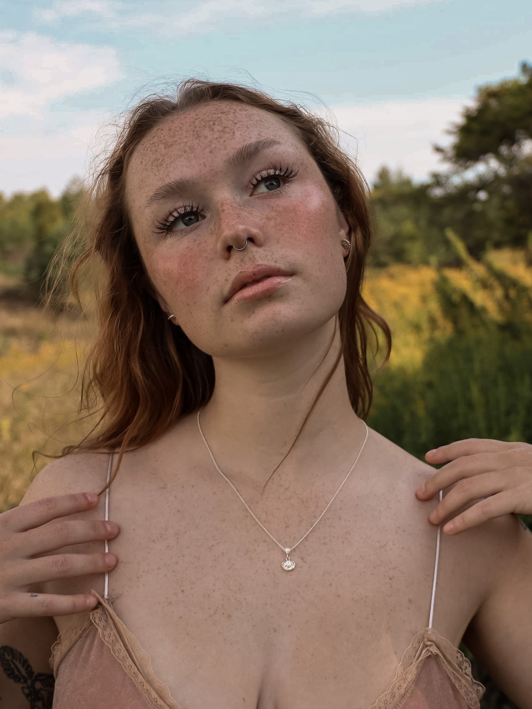 Woman standing in a field looking into the distance while wearing sterling silver fungi studs and fungi pendant.